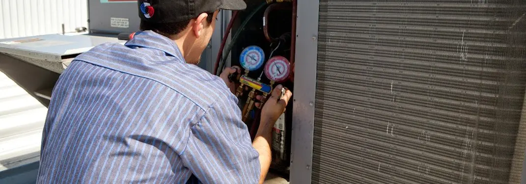 HVAC technician servicing a condenser unit in Blackman