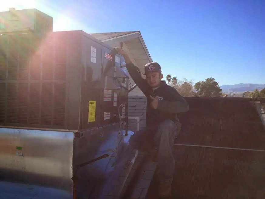 HVAC technician performing AC Tune-Up on a rooftop unit in Blackman
